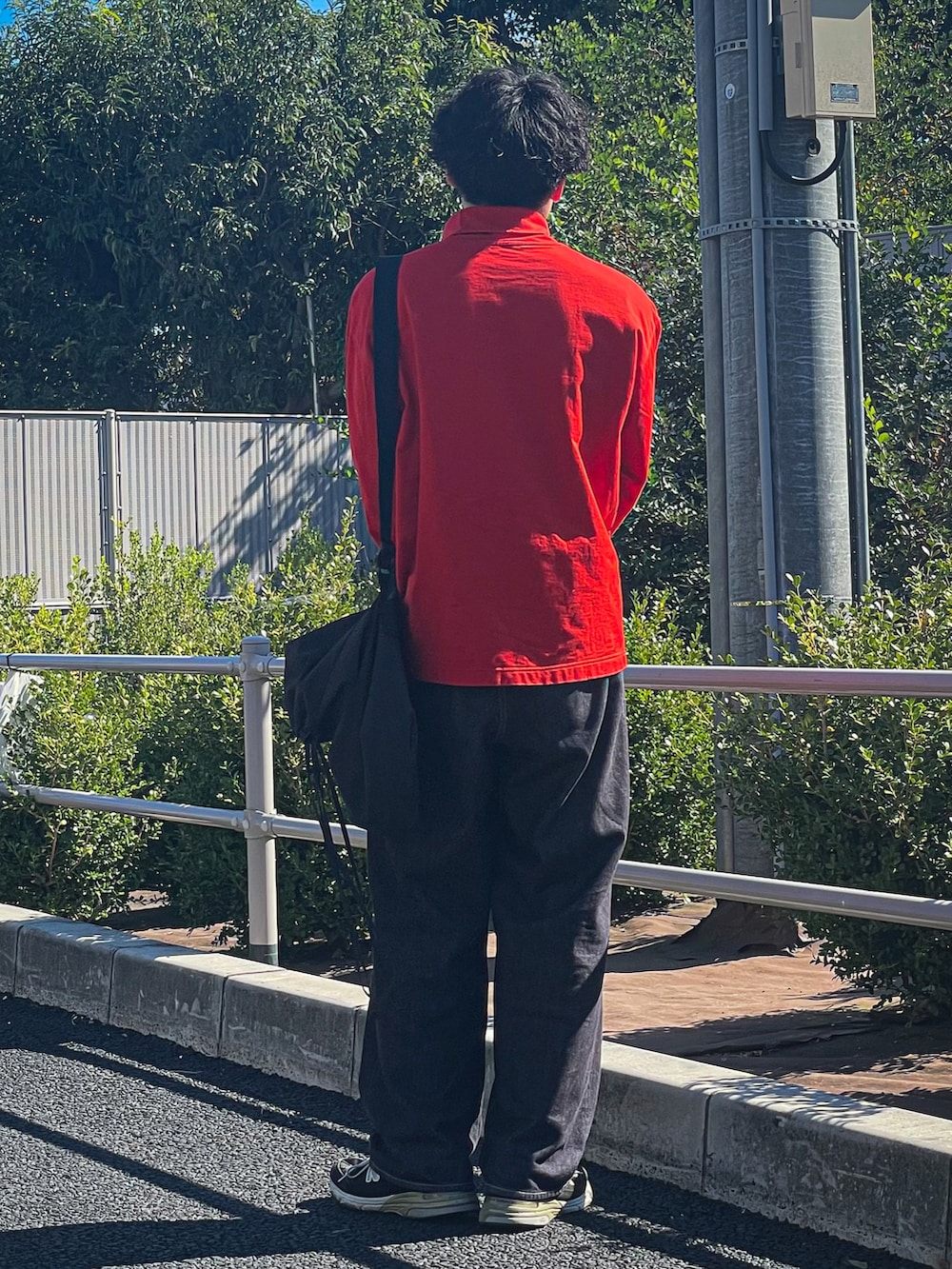 オレンジ系のTシャツ/カットソー、グレー系のバッグ、ブルー系のデニムパンツを着用したメンズの秋コーディネートの2枚目の写真