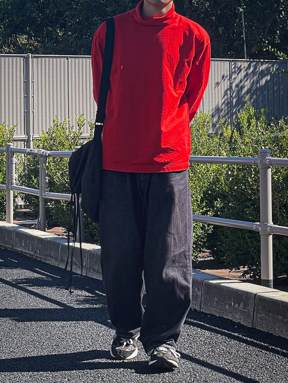 オレンジ系のTシャツ/カットソー、グレー系のバッグ、ブルー系のデニムパンツを着用したメンズの秋コーディネートの3枚目の写真