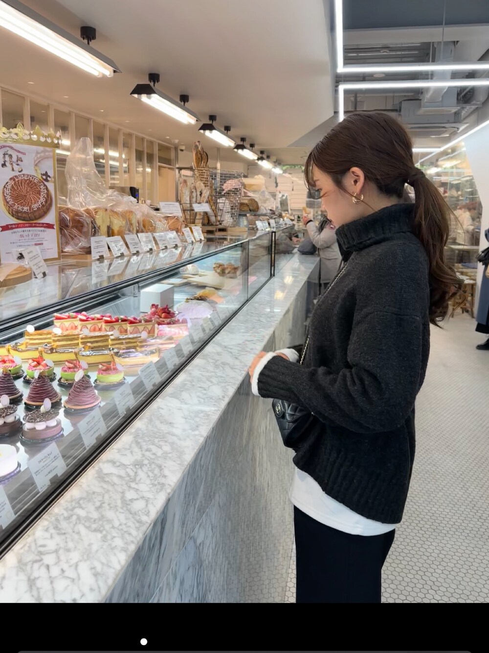 グレー系のニット/セーター、ブラック系のスラックスを着用したレディースの冬コーディネートの2枚目の写真