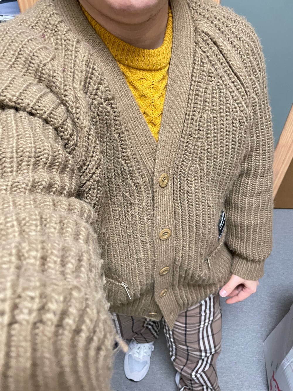 イエロー系のニット/セーター、ブラウン系のカーディガン/ボレロ、ブラウン系のその他パンツを着用したメンズの冬コーディネートの2枚目の写真