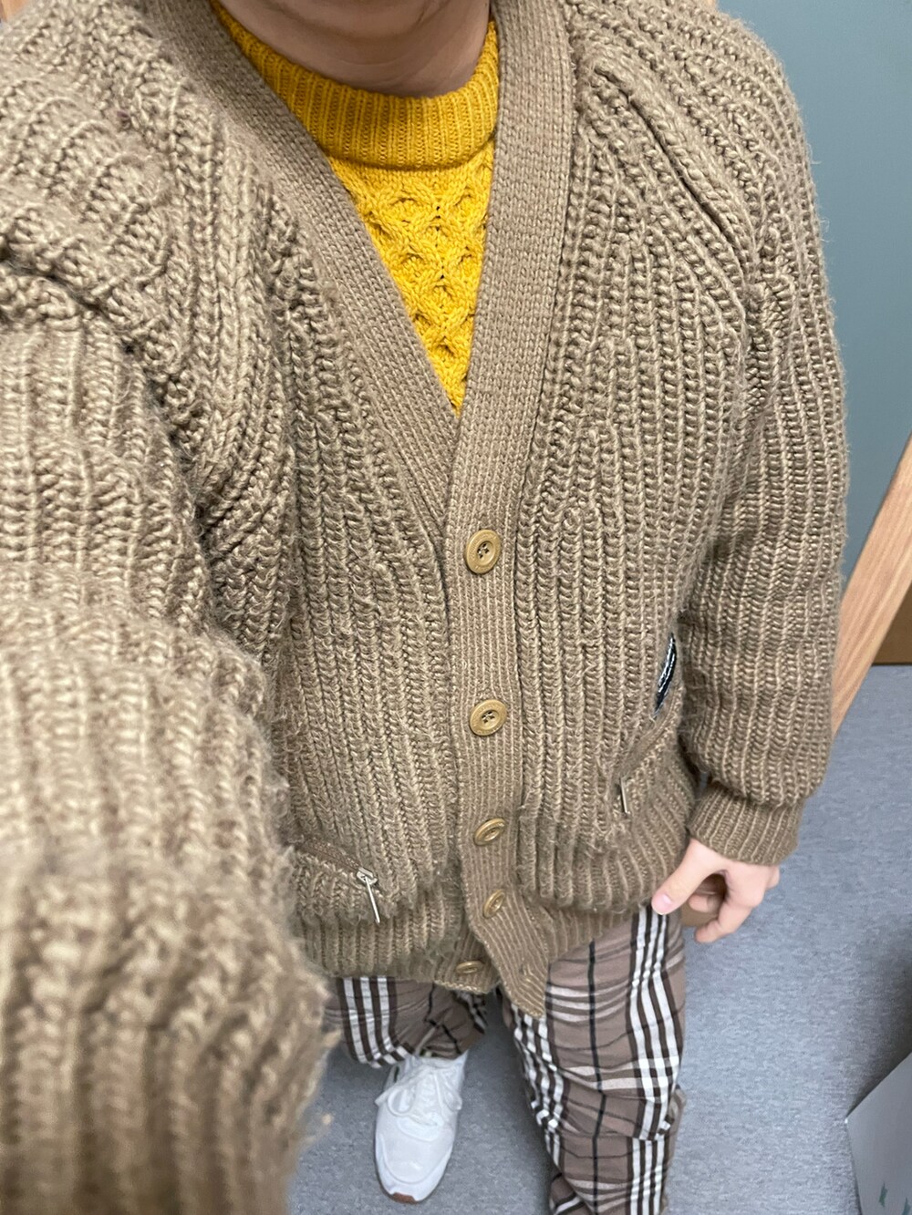 イエロー系のニット/セーター、ブラウン系のカーディガン/ボレロ、ブラウン系のその他パンツを着用したメンズの冬コーディネートの2枚目の写真