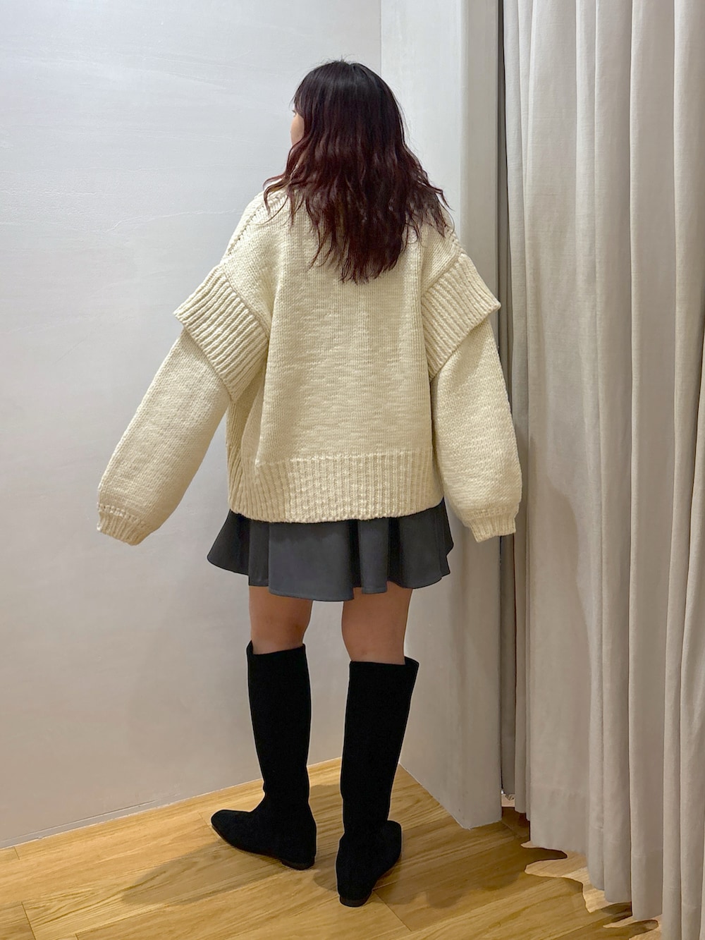 ホワイト系のカーディガン/ボレロ、グレー系のワンピース、ブラック系のブーツを着用したレディースの秋コーディネートの2枚目の写真