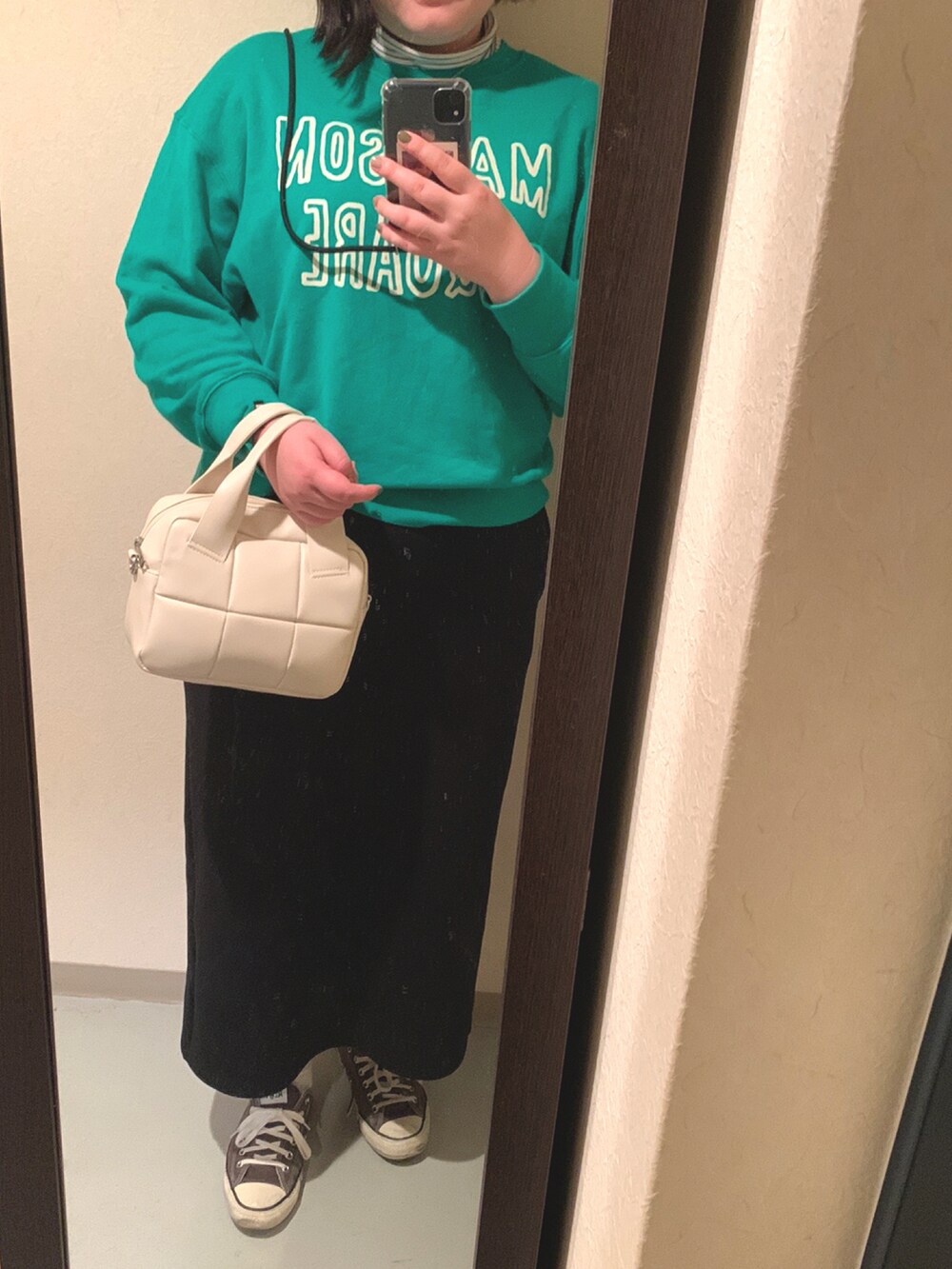 ホワイト系のボストンバッグ、ブラック系のスカート、ブラック系のスニーカーを着用したレディースの秋コーディネートの2枚目の写真