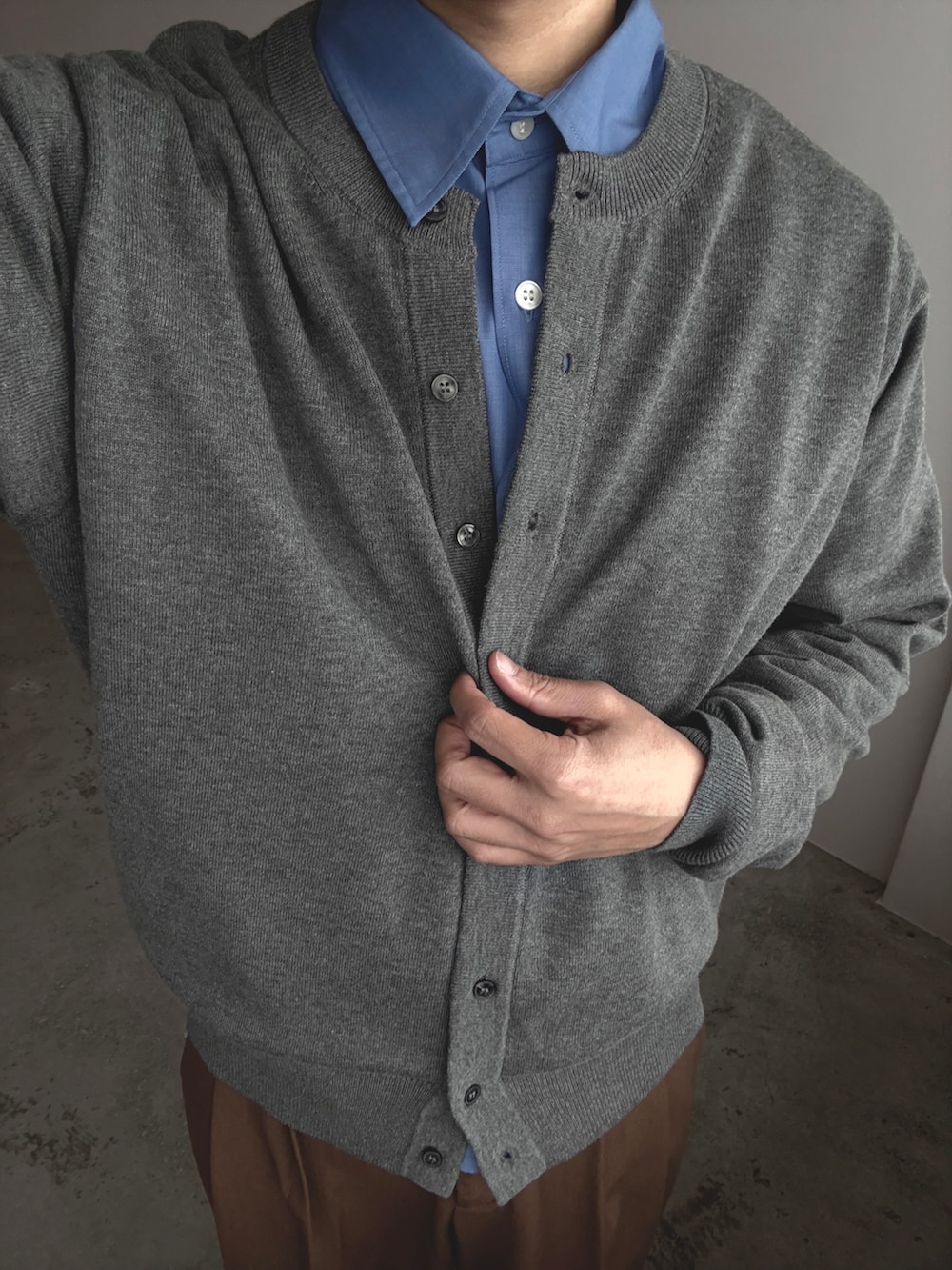 ブラック系のドレスシューズ、ブラウン系のパンツ、グレー系のカーディガン/ボレロを着用したメンズの春コーディネートの2枚目の写真