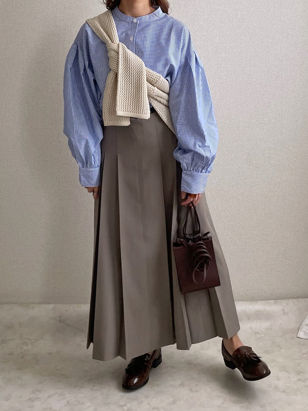 ブルー系のシャツ/ブラウス、ベージュ系のハンドバッグ、グレー系のスカートを着用したレディースの春コーディネートの2枚目の写真