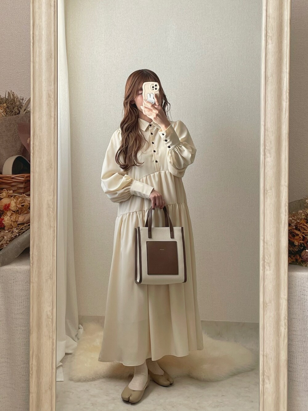 ベージュ系のトートバッグ、ホワイト系のシャツワンピース、ベージュ系のパンプスを着用したレディースの冬コーディネートの2枚目の写真