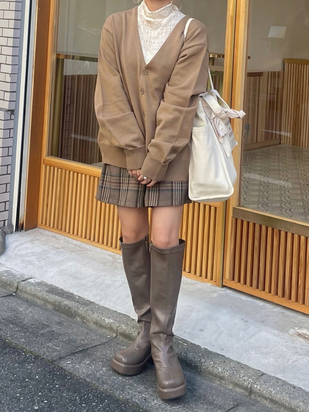 ベージュ系のカーディガン/ボレロ、ホワイト系のシャツ/ブラウス、ブラウン系のセットアップを着用したレディースの秋コーディネートの2枚目の写真