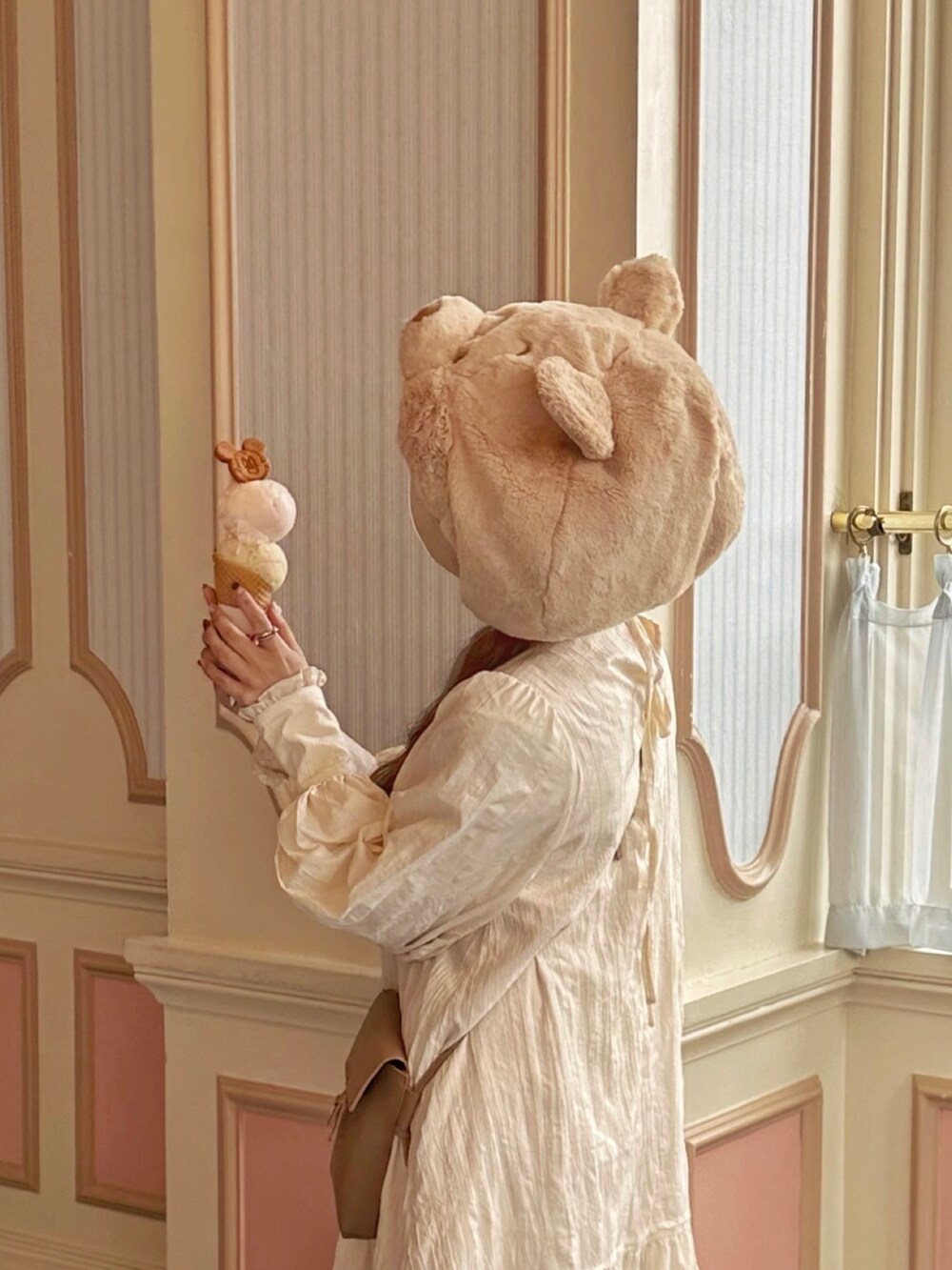 ベージュ系のカーディガン/ボレロ、ホワイト系のワンピース、ベージュ系のショルダーバッグを着用したレディースの秋コーディネートの2枚目の写真