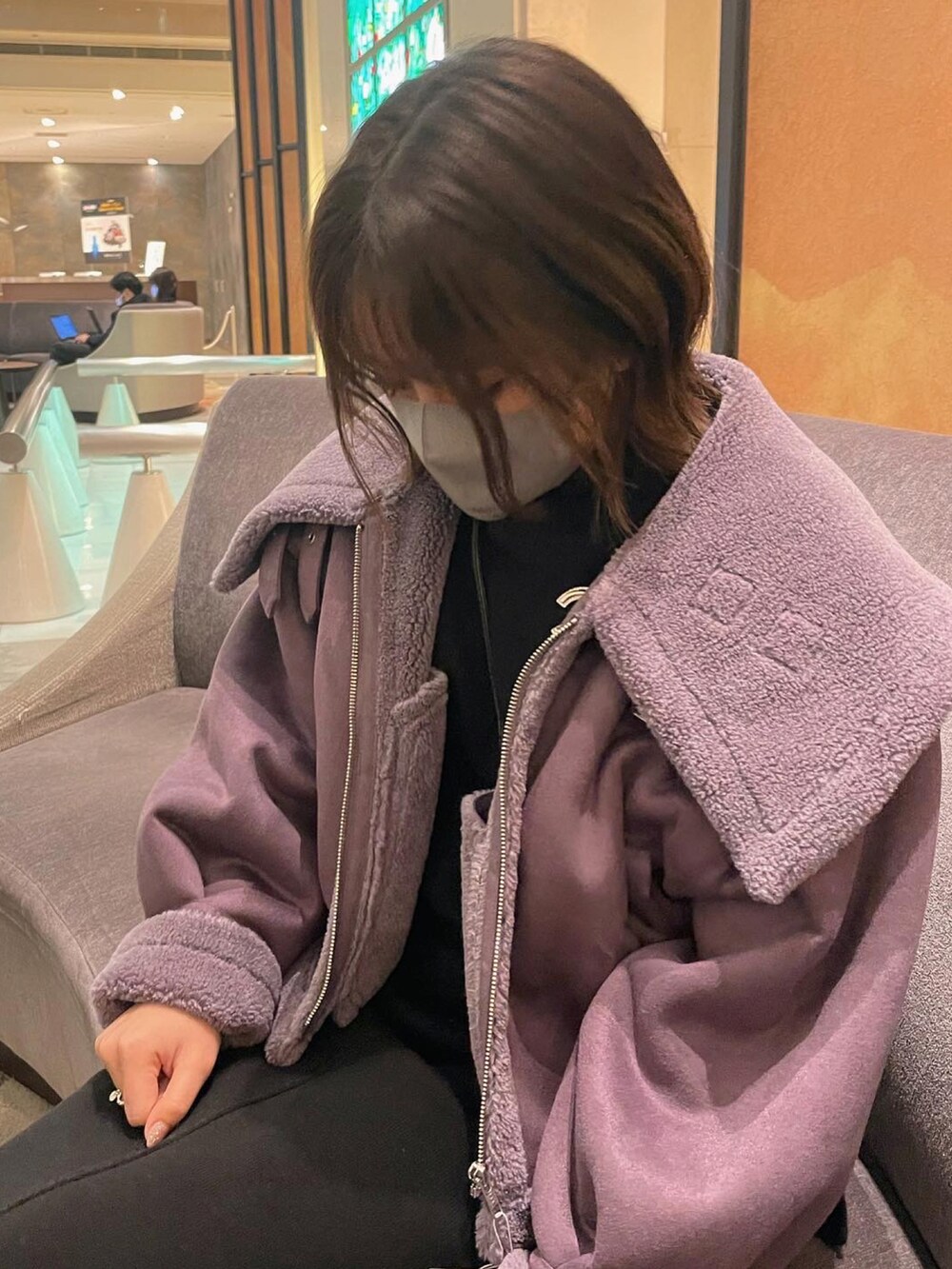 パープル系のムートンコート、ブラック系のニット/セーター、ブラック系のスカートを着用したレディースの冬コーディネートの2枚目の写真