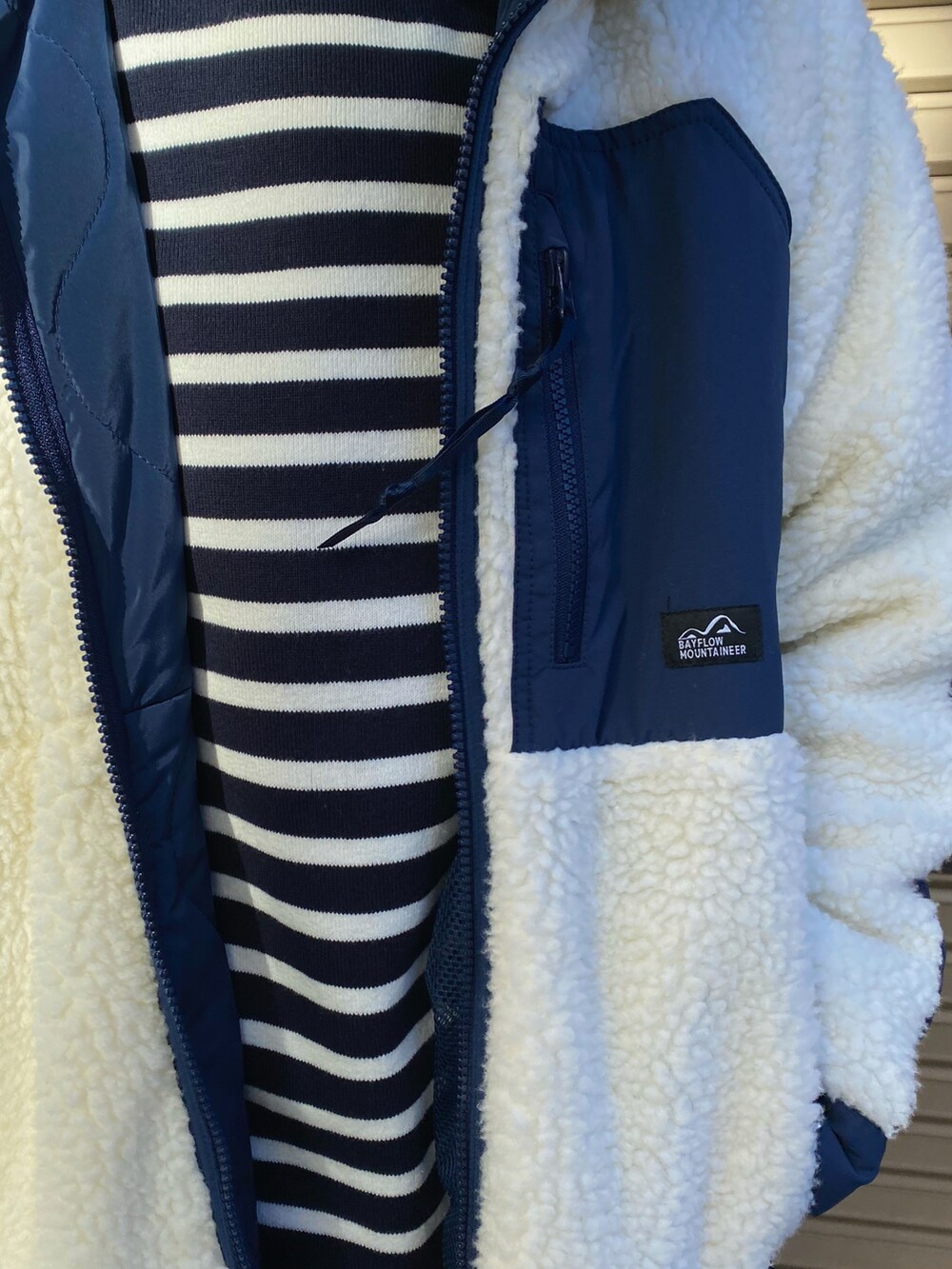 ブルー系のニット/セーター、ホワイト系のブルゾン、ブルー系のデニムパンツを着用したレディースの秋コーディネートの5枚目の写真