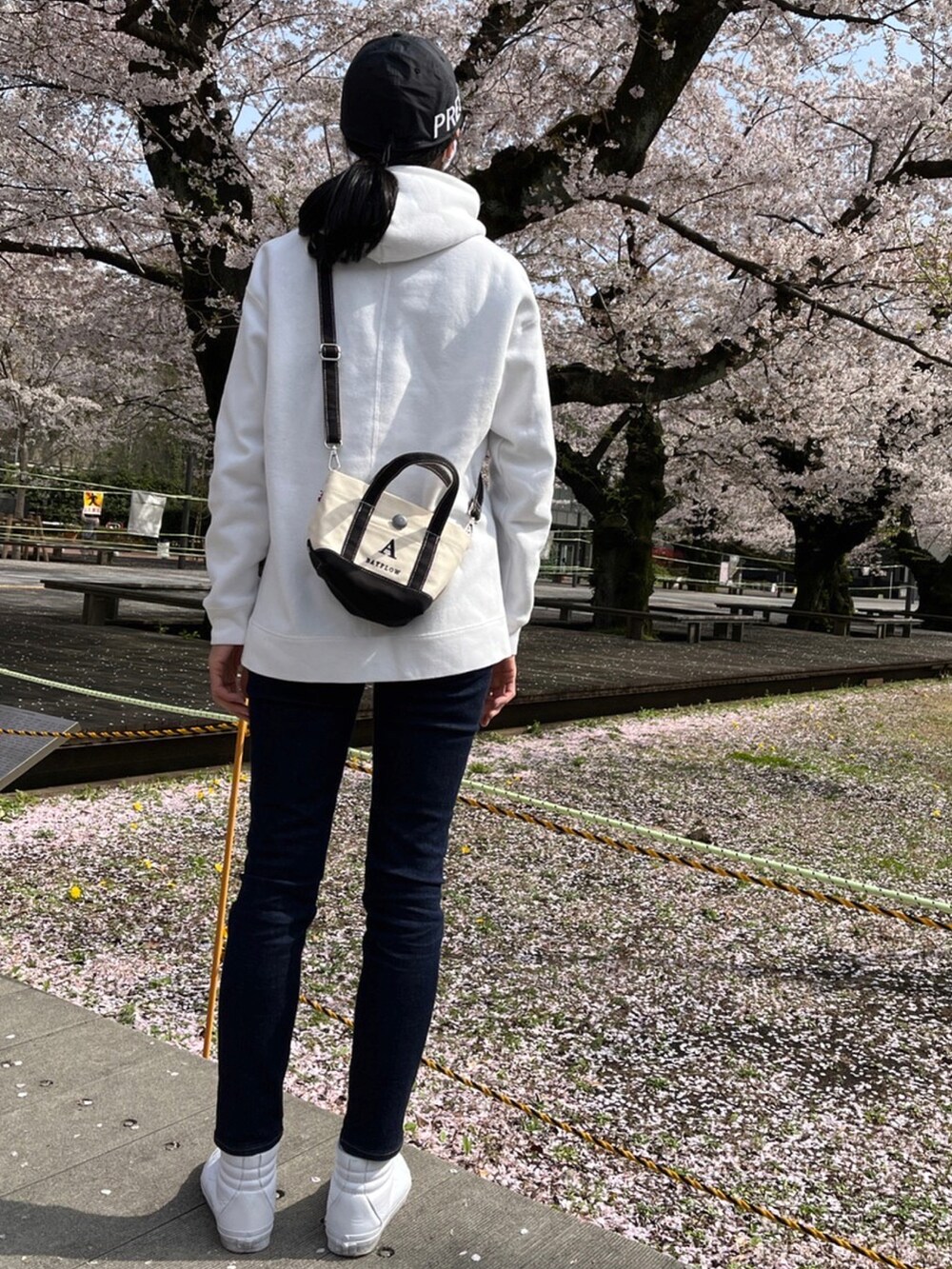 ホワイト系のバッグ、ブルー系のデニムパンツ、ホワイト系のスニーカーを着用したレディースの春コーディネートの2枚目の写真