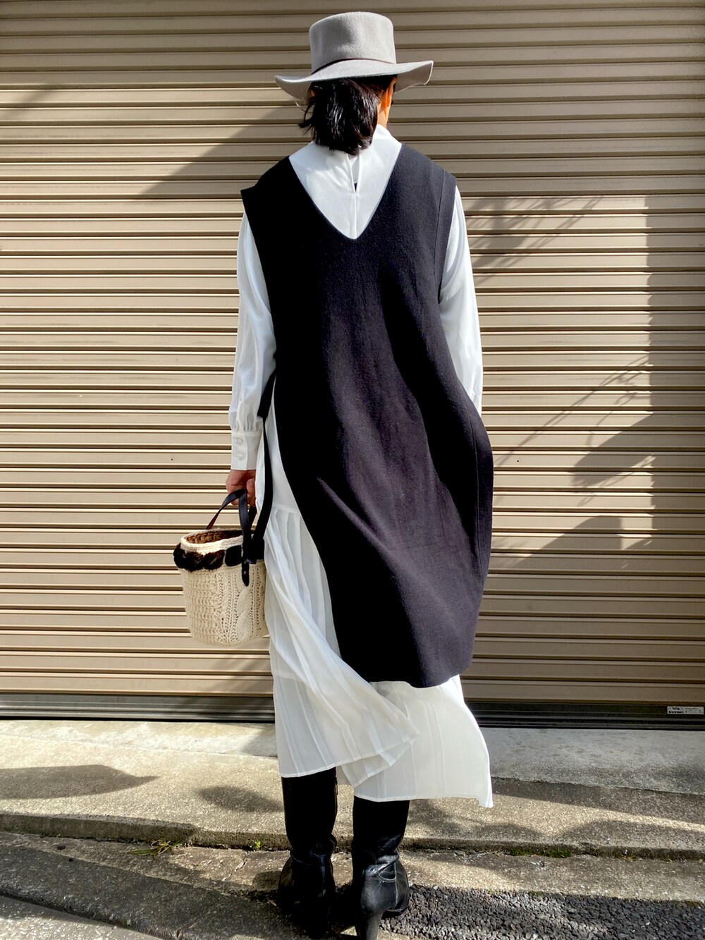 ブラック系のベスト、ホワイト系のワンピース、ブラック系のブーツを着用したレディースの秋コーディネートの3枚目の写真