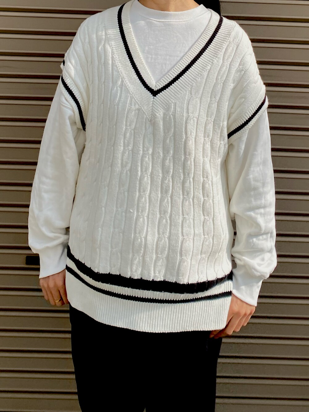 ホワイト系のベスト、ホワイト系のスウェット、ブラック系のパンツを着用したレディースの秋コーディネートの2枚目の写真