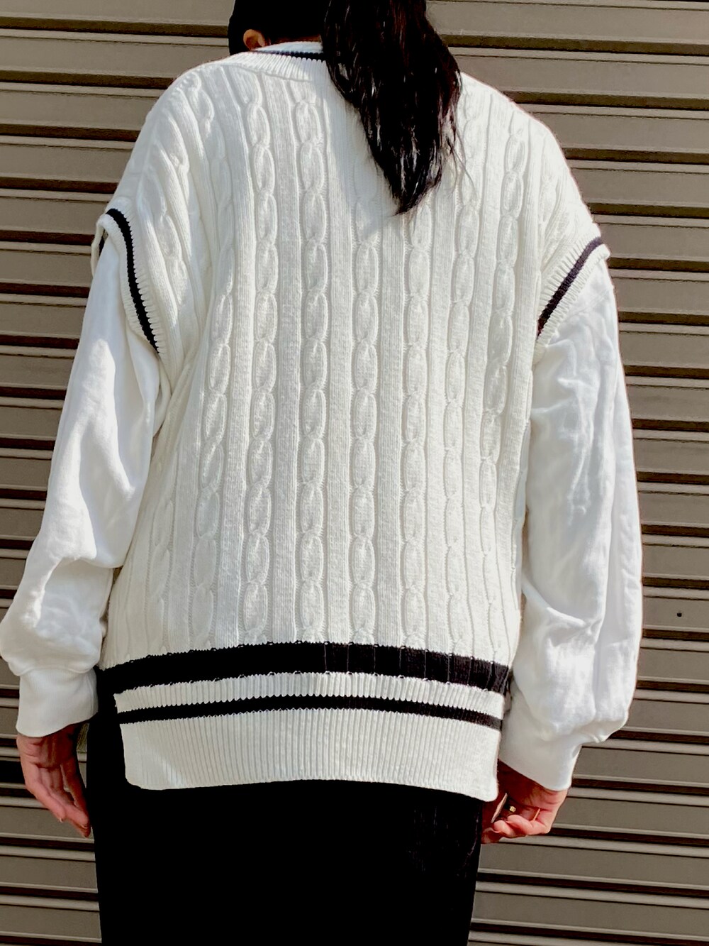 ホワイト系のベスト、ホワイト系のスウェット、ブラック系のパンツを着用したレディースの秋コーディネートの3枚目の写真