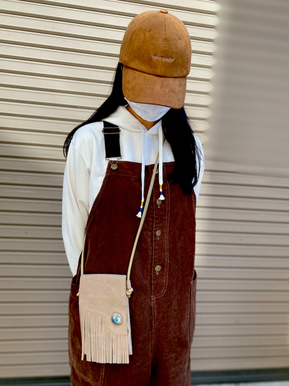 ホワイト系のパーカー、ベージュ系のショルダーバッグ、ブラウン系のサロペット/オーバーオールを着用したレディースの秋コーディネートの5枚目の写真