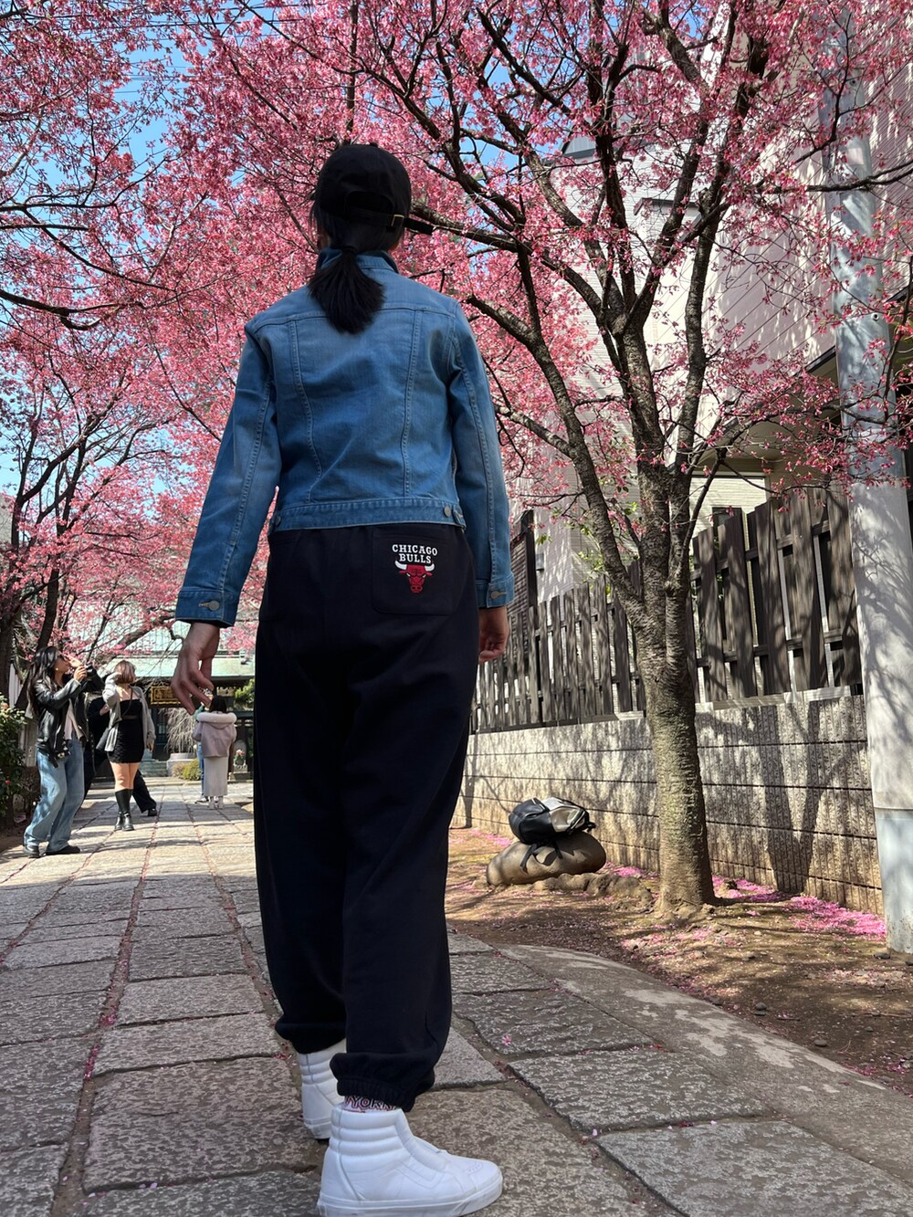 ブラック系のスウェットパンツ、ホワイト系のスニーカーを着用したレディースの春コーディネートの2枚目の写真