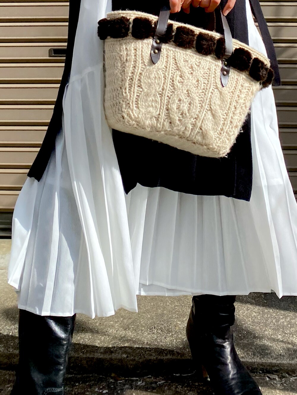 ブラック系のベスト、ホワイト系のワンピース、ブラック系のブーツを着用したレディースの秋コーディネートの2枚目の写真