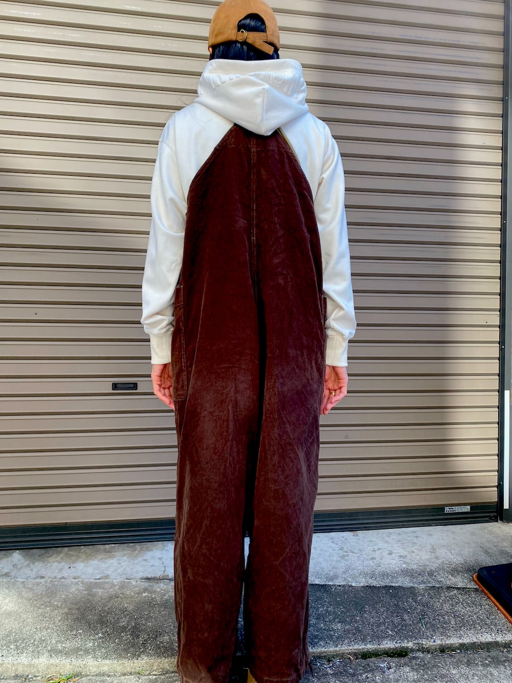 ホワイト系のパーカー、ベージュ系のショルダーバッグ、ブラウン系のサロペット/オーバーオールを着用したレディースの秋コーディネートの3枚目の写真