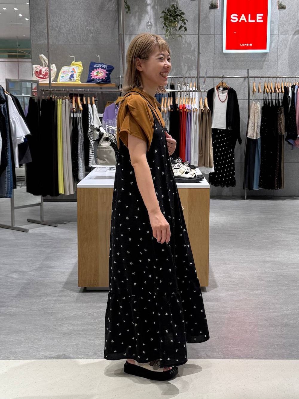 ブラック系のワンピース、ホワイト系のサンダル、イエロー系のTシャツ/カットソーを着用したレディースの夏コーディネートの4枚目の写真