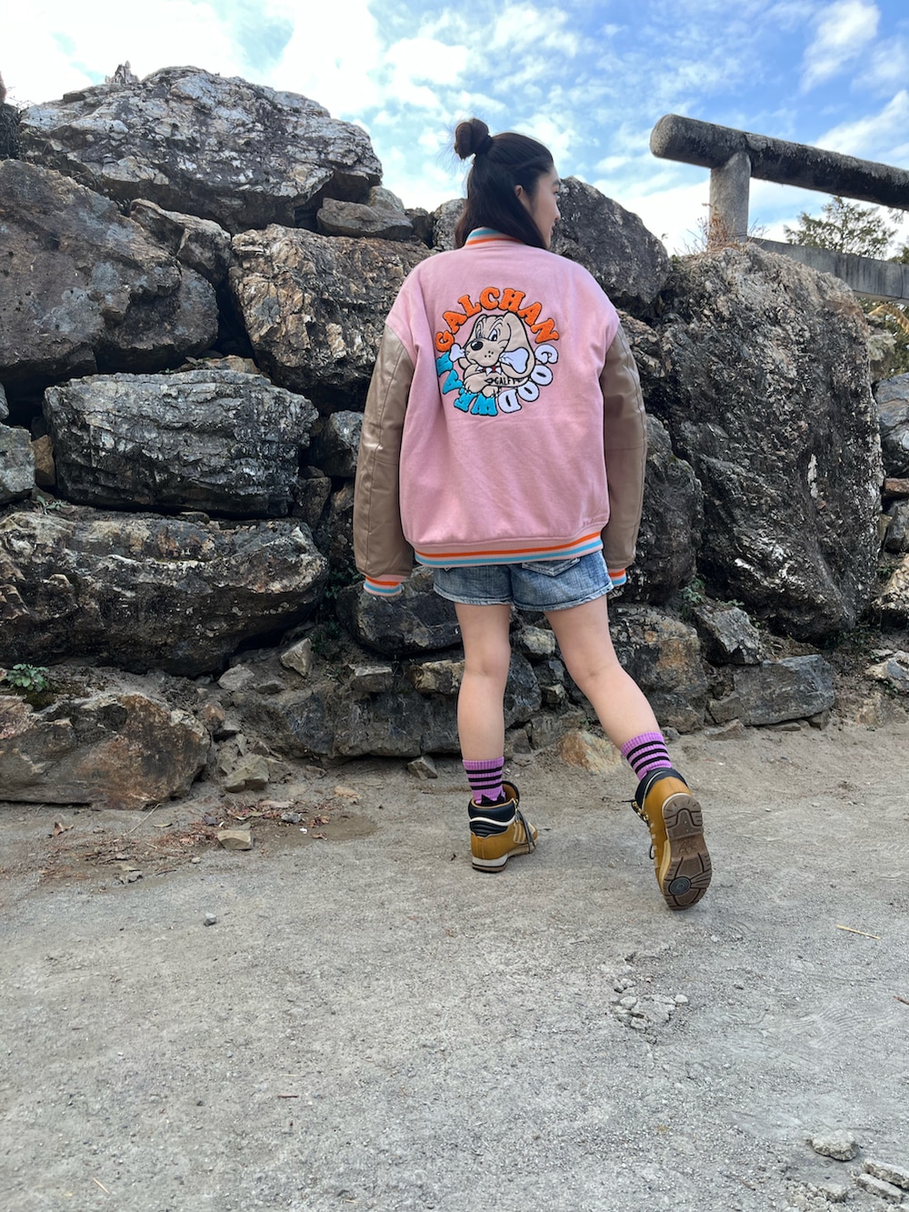 グレー系のトップス、ブラウン系のスニーカー、ピンク系のスタジャンを着用したレディースの冬コーディネートの2枚目の写真