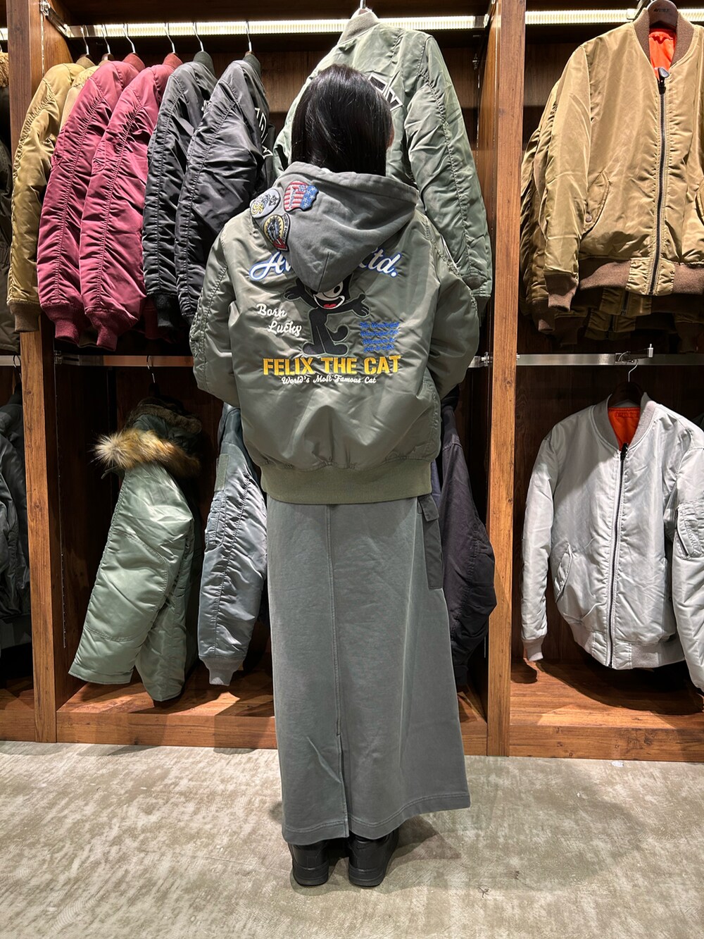 グレー系のパーカー、グレー系のスカート、グリーン系のMA-1を着用したレディースの冬コーディネートの2枚目の写真