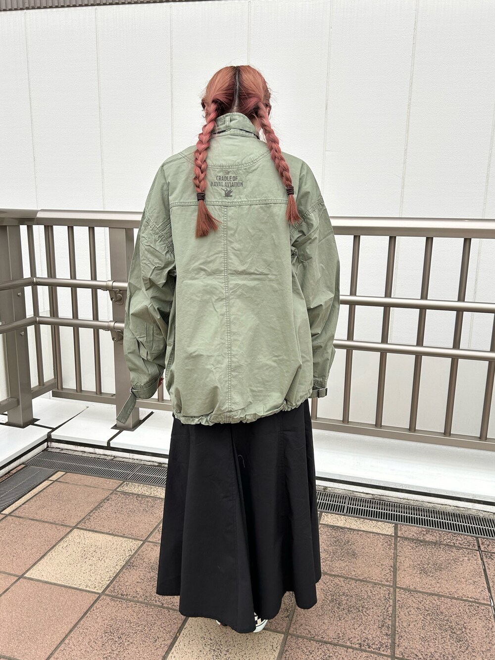 グリーン系のその他アウター、ブラック系のスカート、ホワイト系のTシャツ/カットソーを着用したレディースの春コーディネートの2枚目の写真