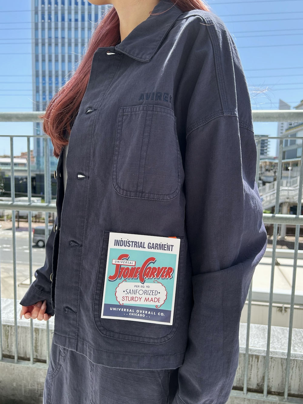 ブルー系のカバーオール、ブルー系のスカート、ブラック系のキャップを着用したレディースの春コーディネートの3枚目の写真