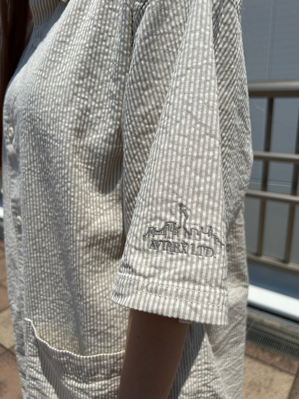 グレー系のシャツ/ブラウス、ブラウン系のトートバッグ、ホワイト系のソックス/靴下を着用したレディースの夏コーディネートの3枚目の写真