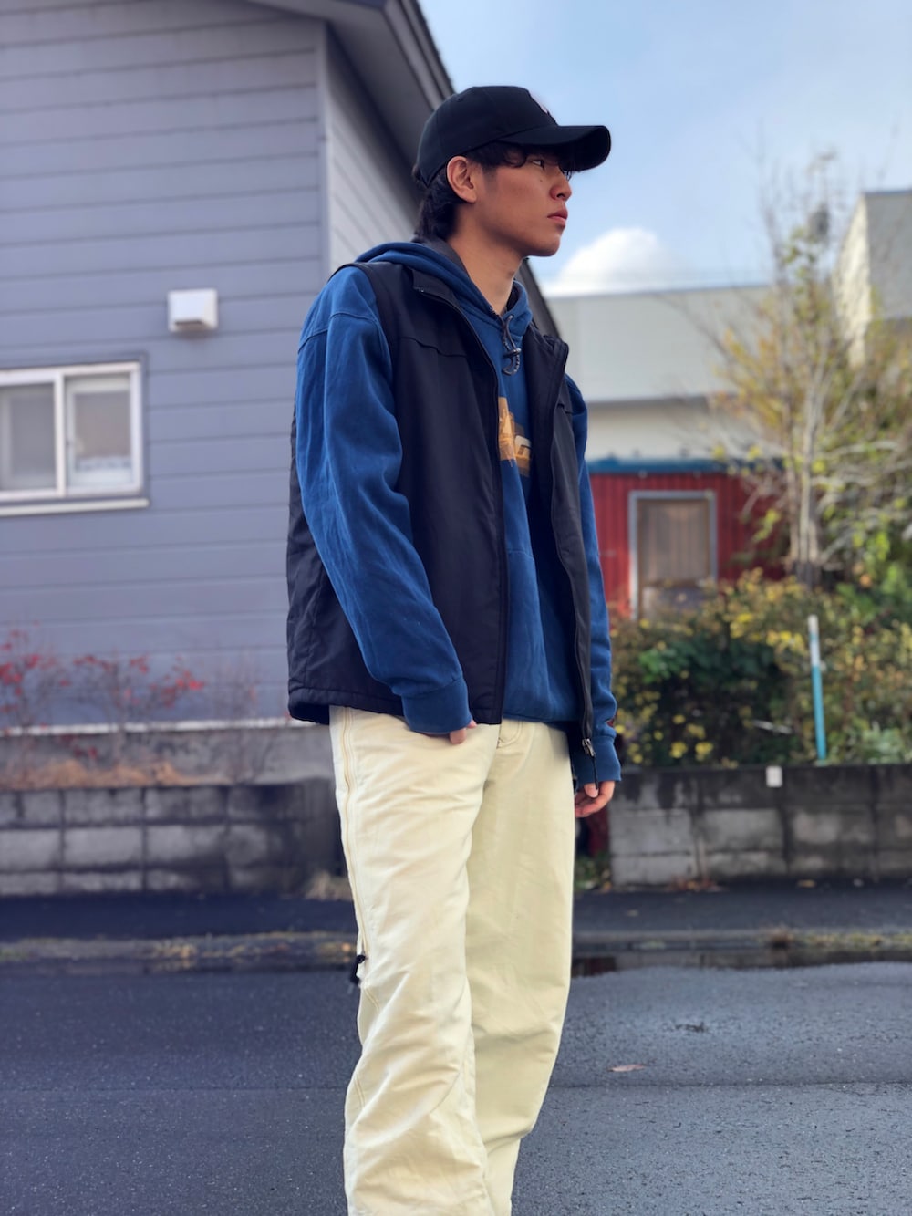 ホワイト系のその他パンツ、ブラック系のスニーカー、ブラック系のベストを着用したメンズの秋コーディネートの2枚目の写真