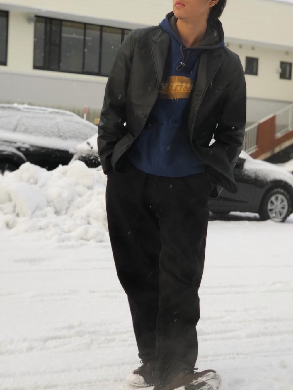 ブラック系のテーラードジャケット、ブルー系のパーカー、ブラック系のデニムパンツを着用したメンズの冬コーディネートの2枚目の写真