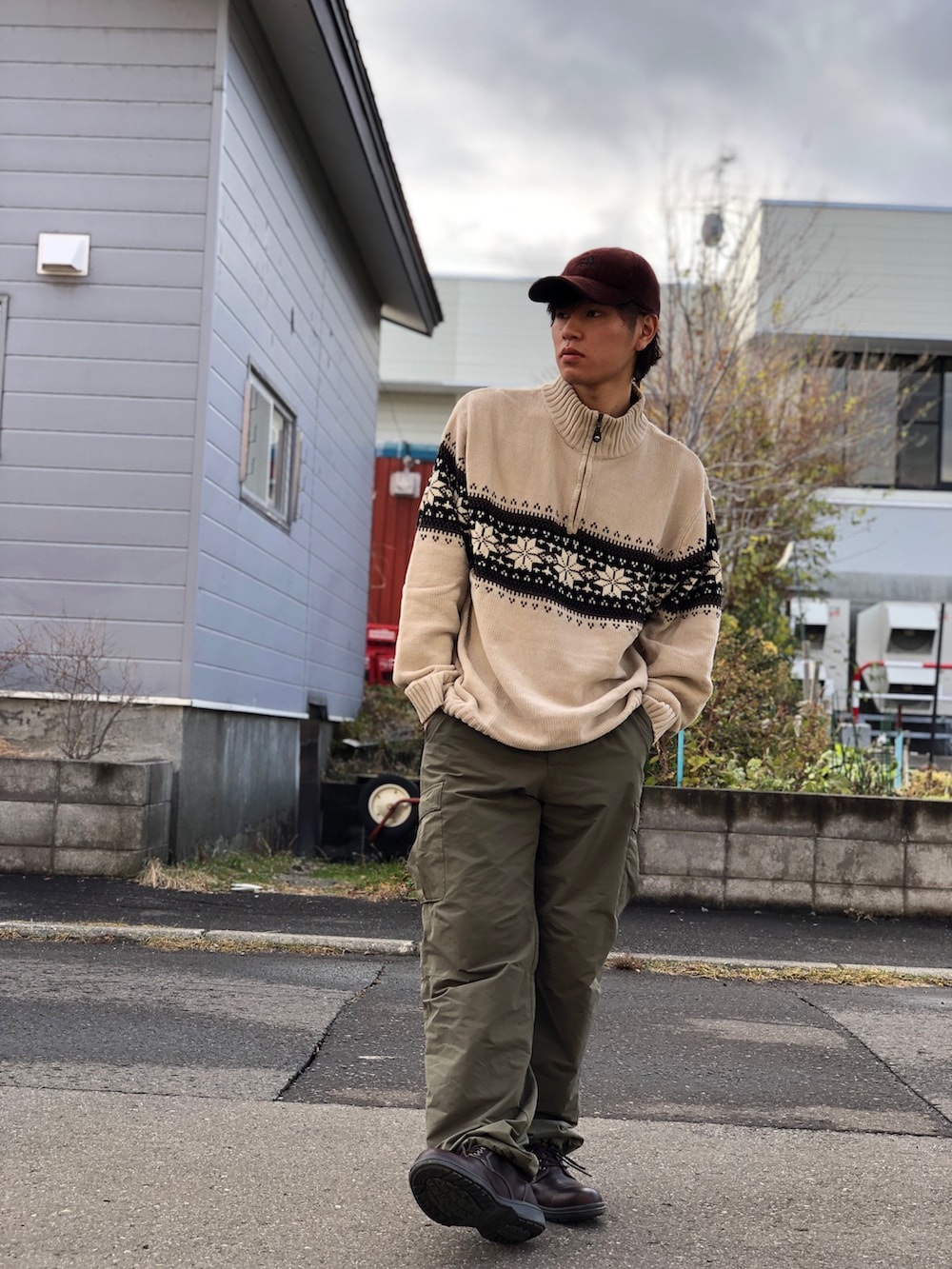 グリーン系のカーゴパンツ、ブラウン系のブーツ、ベージュ系のニット/セーターを着用したメンズの秋コーディネートの2枚目の写真