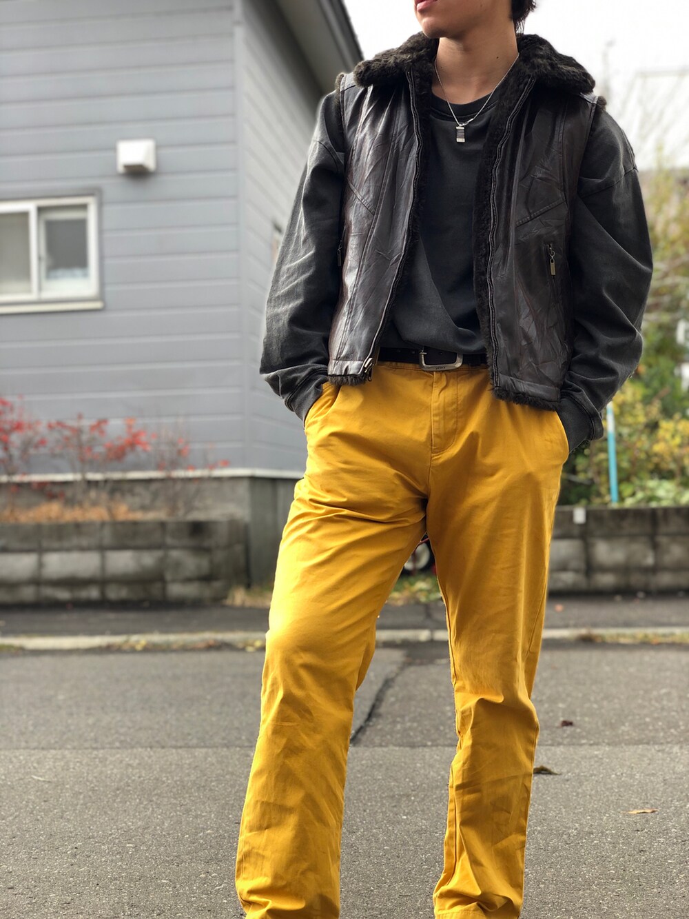 イエロー系のパンツ、ブラウン系のブーツ、ブラウン系のベストを着用したメンズの秋コーディネートの3枚目の写真