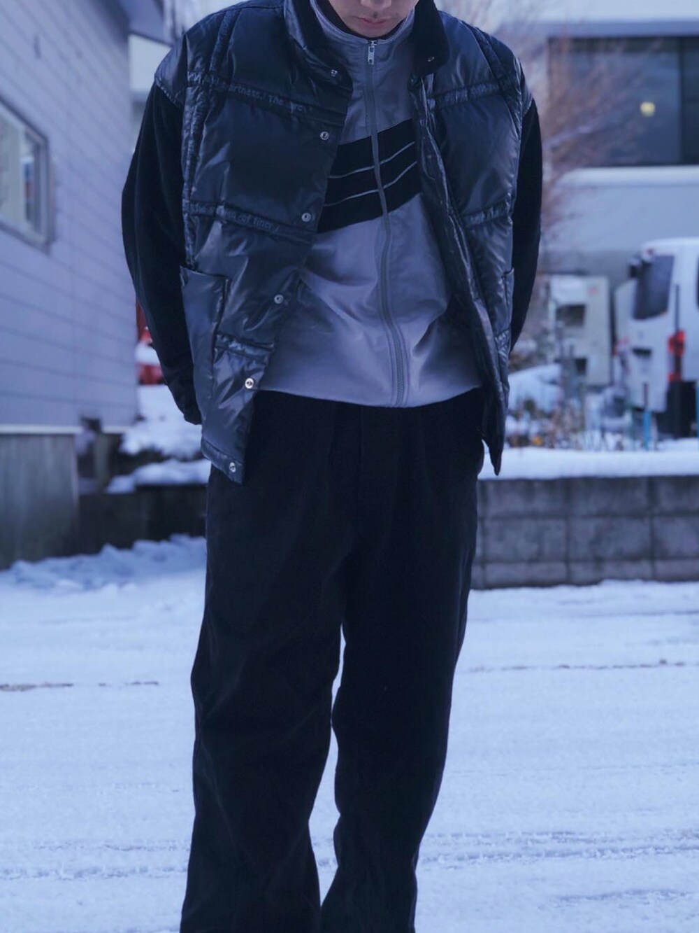 ブラック系のダウンベスト、シルバー系のジャージ、ブラック系のデニムパンツを着用したメンズの冬コーディネートの2枚目の写真