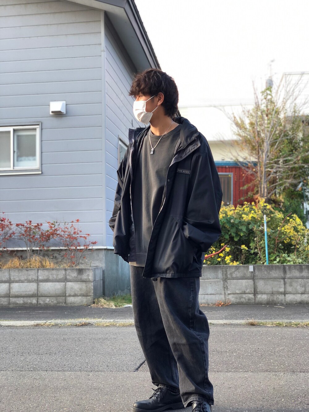 ブラック系のTシャツ/カットソー、ブラック系のナイロンジャケット、ブルー系のデニムパンツを着用したメンズの秋コーディネートの2枚目の写真