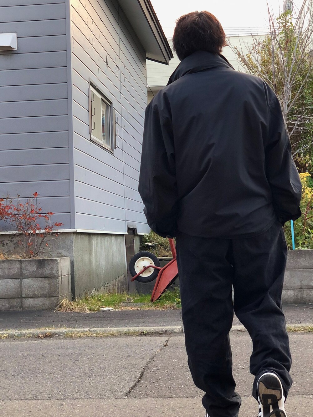 ブラック系のナイロンジャケット、ホワイト系のTシャツ/カットソー、ブラック系のデニムパンツを着用したメンズの秋コーディネートの2枚目の写真