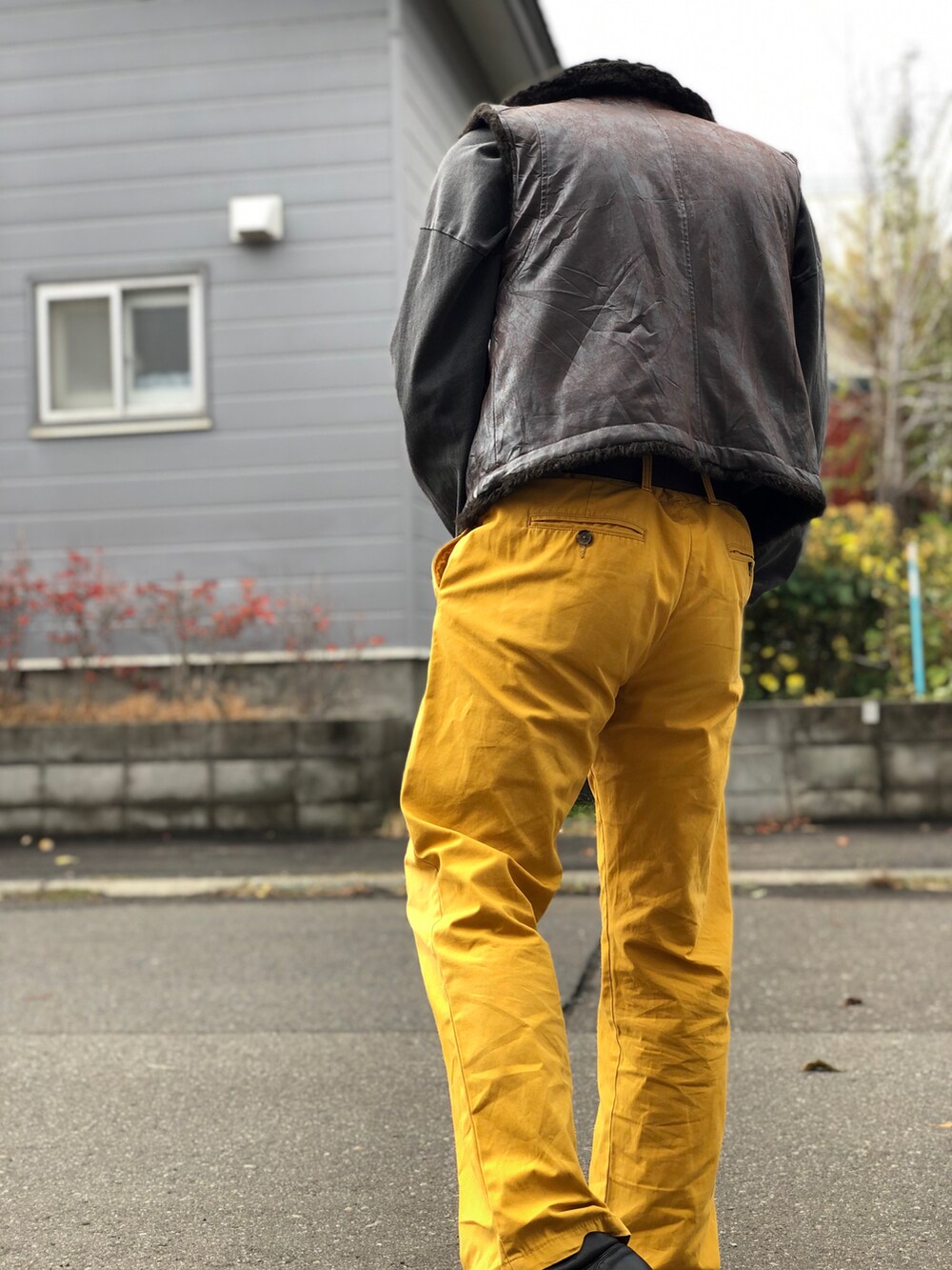 イエロー系のパンツ、ブラウン系のブーツ、ブラウン系のベストを着用したメンズの秋コーディネートの2枚目の写真