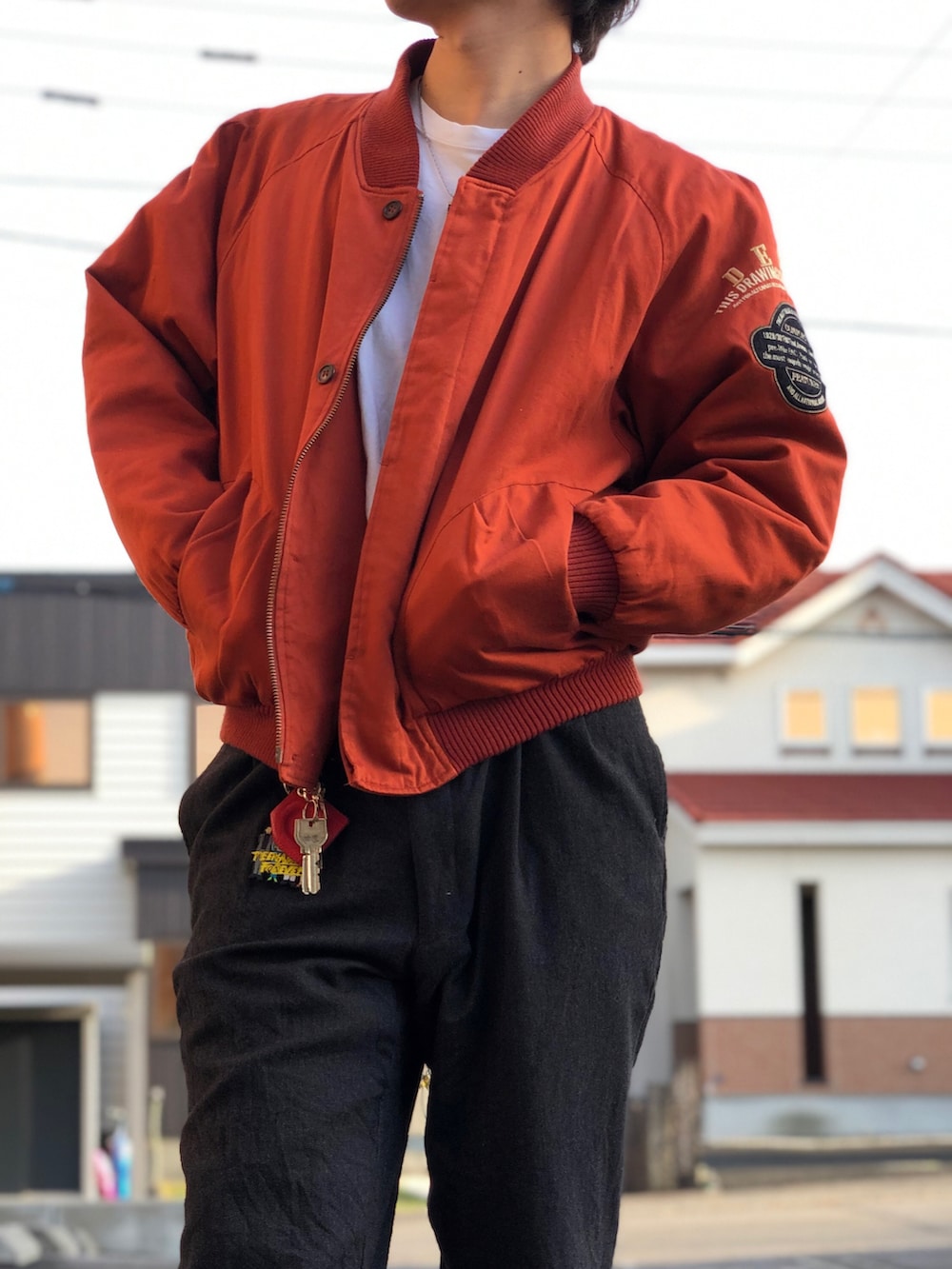 オレンジ系のスタジャン、ブラック系のスラックス、ブラック系のドレスシューズを着用したメンズの秋コーディネートの3枚目の写真