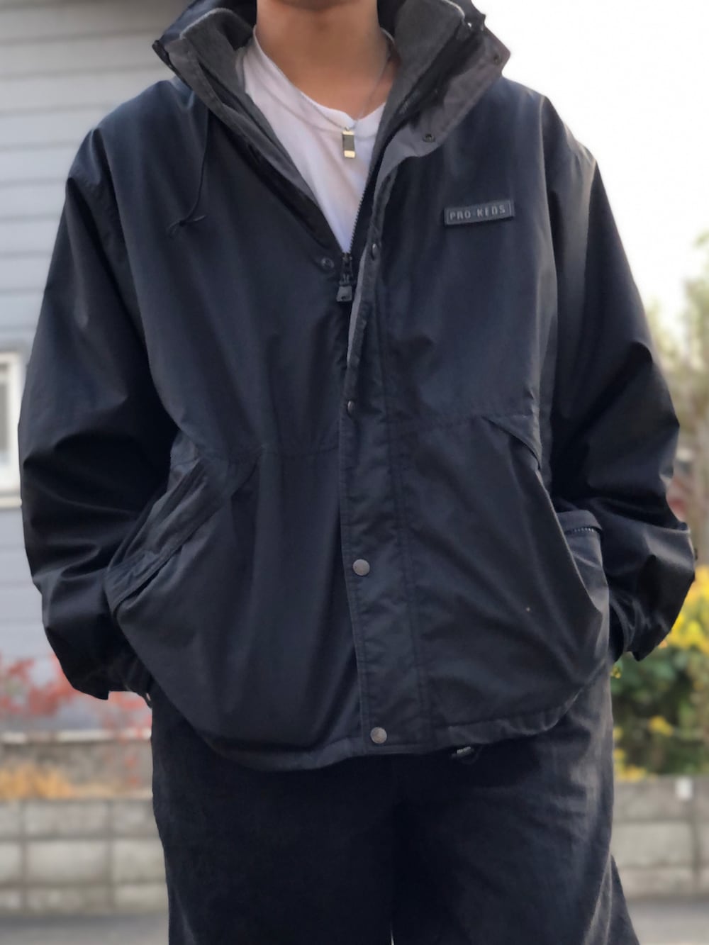 ブラック系のナイロンジャケット、ホワイト系のTシャツ/カットソー、ブラック系のデニムパンツを着用したメンズの秋コーディネートの3枚目の写真