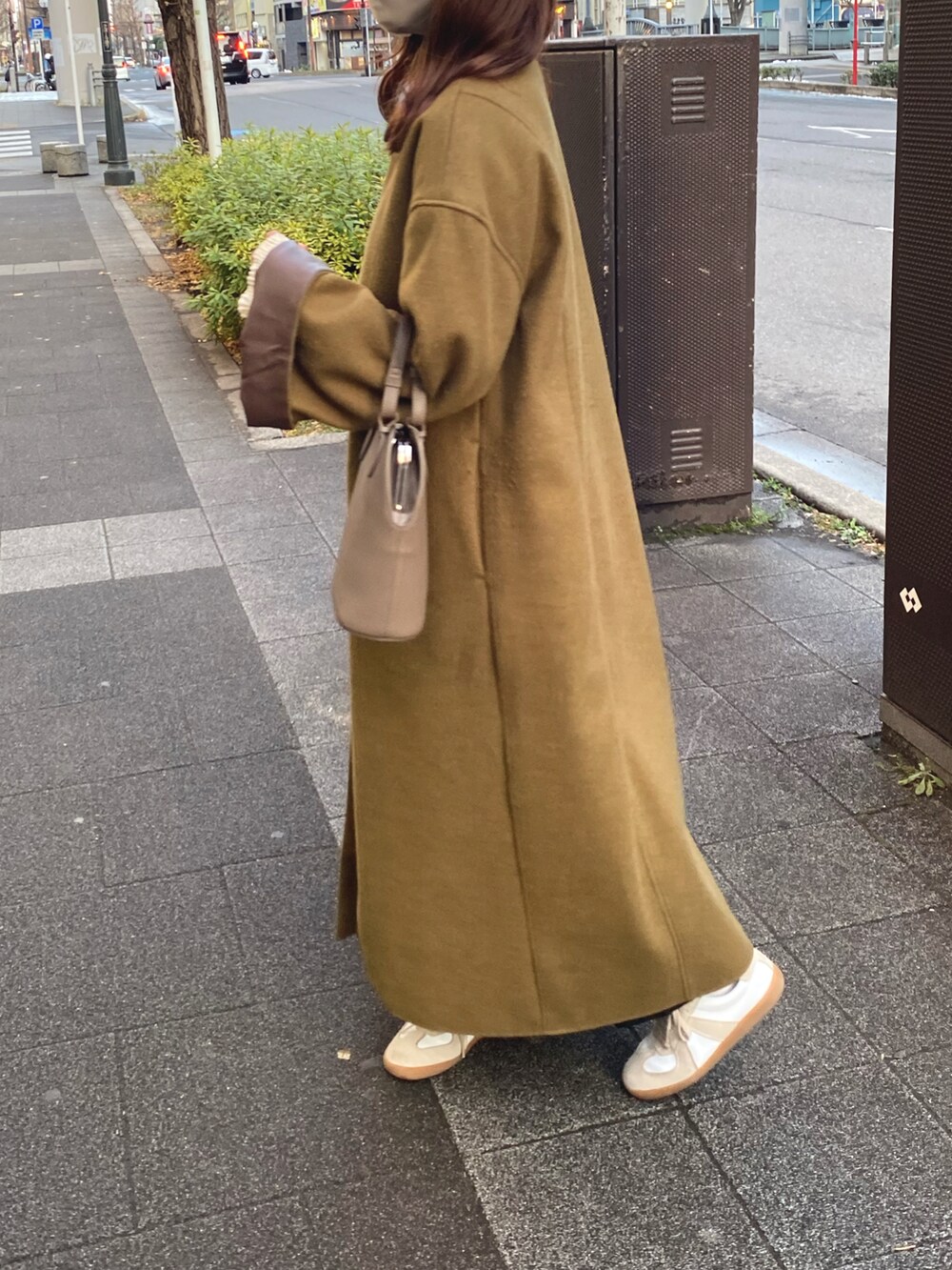 ベージュ系のベスト、ベージュ系のハンドバッグ、ホワイト系のシャツ/ブラウスを着用したレディースの春コーディネートの2枚目の写真