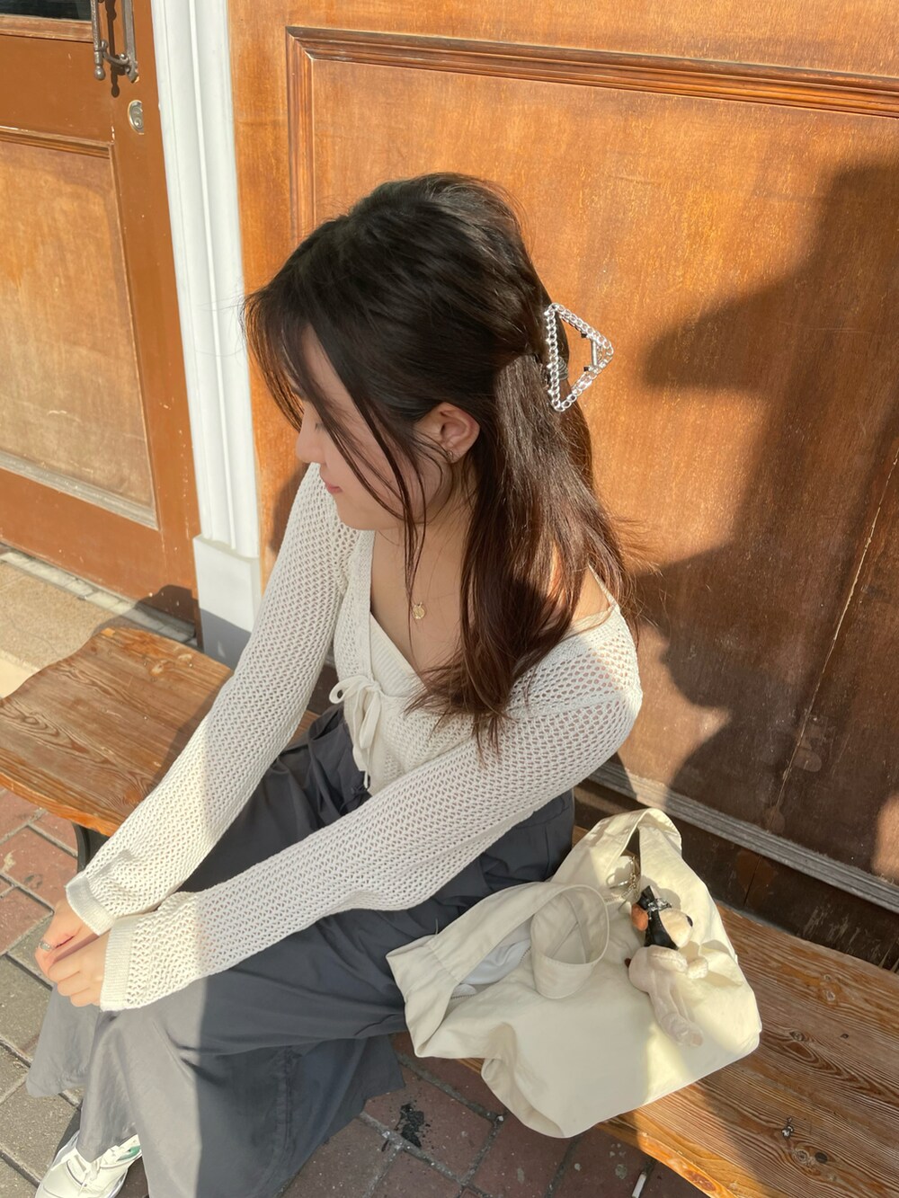 ホワイト系のカーディガン/ボレロ、ホワイト系のショルダーバッグ、グレー系のスカートを着用したレディースの秋コーディネートの2枚目の写真