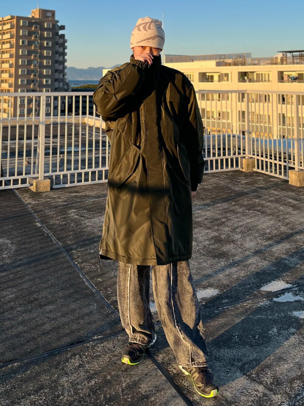 ブラック系のデニムパンツ、ブラック系のスニーカー、グリーン系のダウンジャケット/コートを着用したメンズの冬コーディネートの2枚目の写真