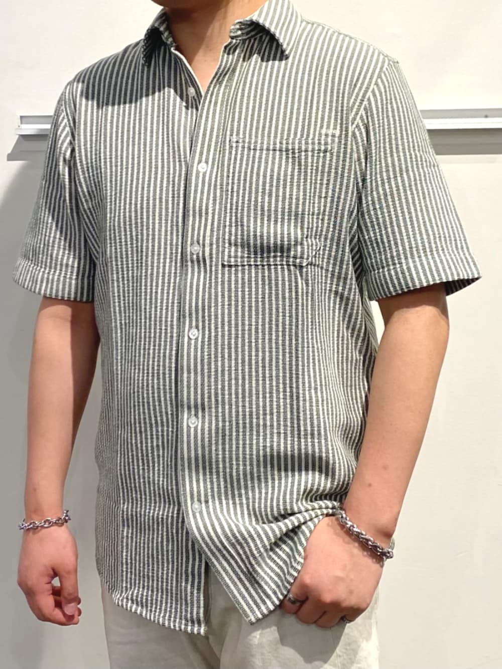 グレー系のデニムパンツ、グリーン系のシャツ/ブラウス、ブラック系のサンダルを着用したメンズの夏コーディネートの2枚目の写真