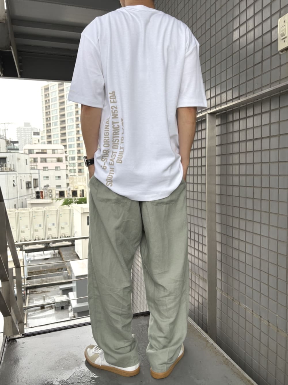 グリーン系のスラックス、ホワイト系のTシャツ/カットソーを着用したメンズの夏コーディネートの4枚目の写真
