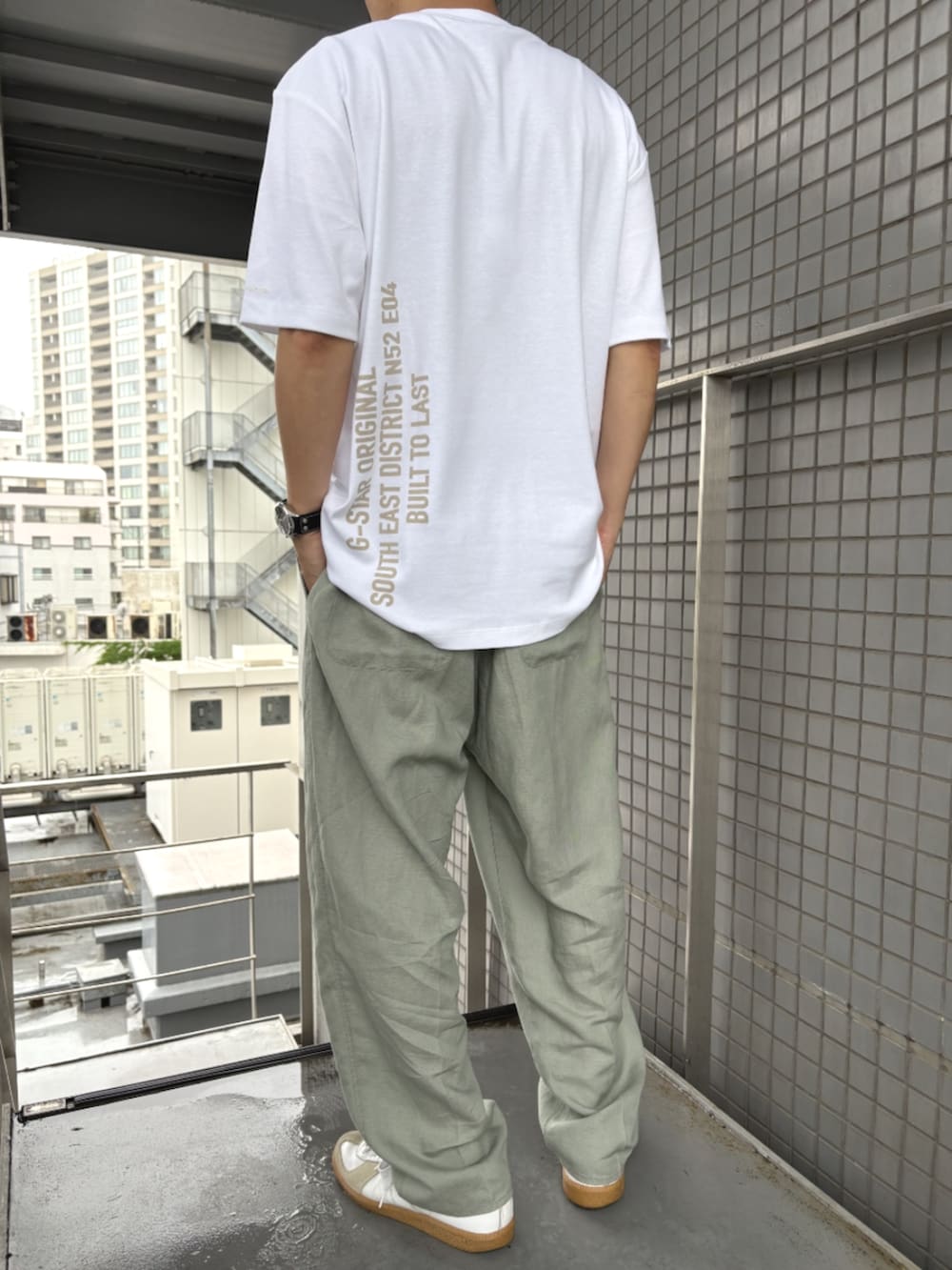 グリーン系のスラックス、ホワイト系のTシャツ/カットソーを着用したメンズの夏コーディネートの3枚目の写真