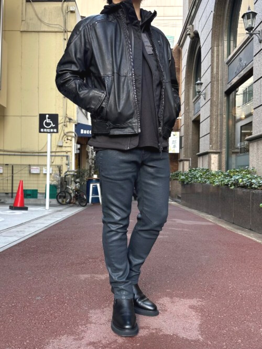 ブラック系のライダースジャケット、ブラック系のナイロンジャケット、ブルー系のデニムパンツを着用したメンズの冬コーディネートの2枚目の写真