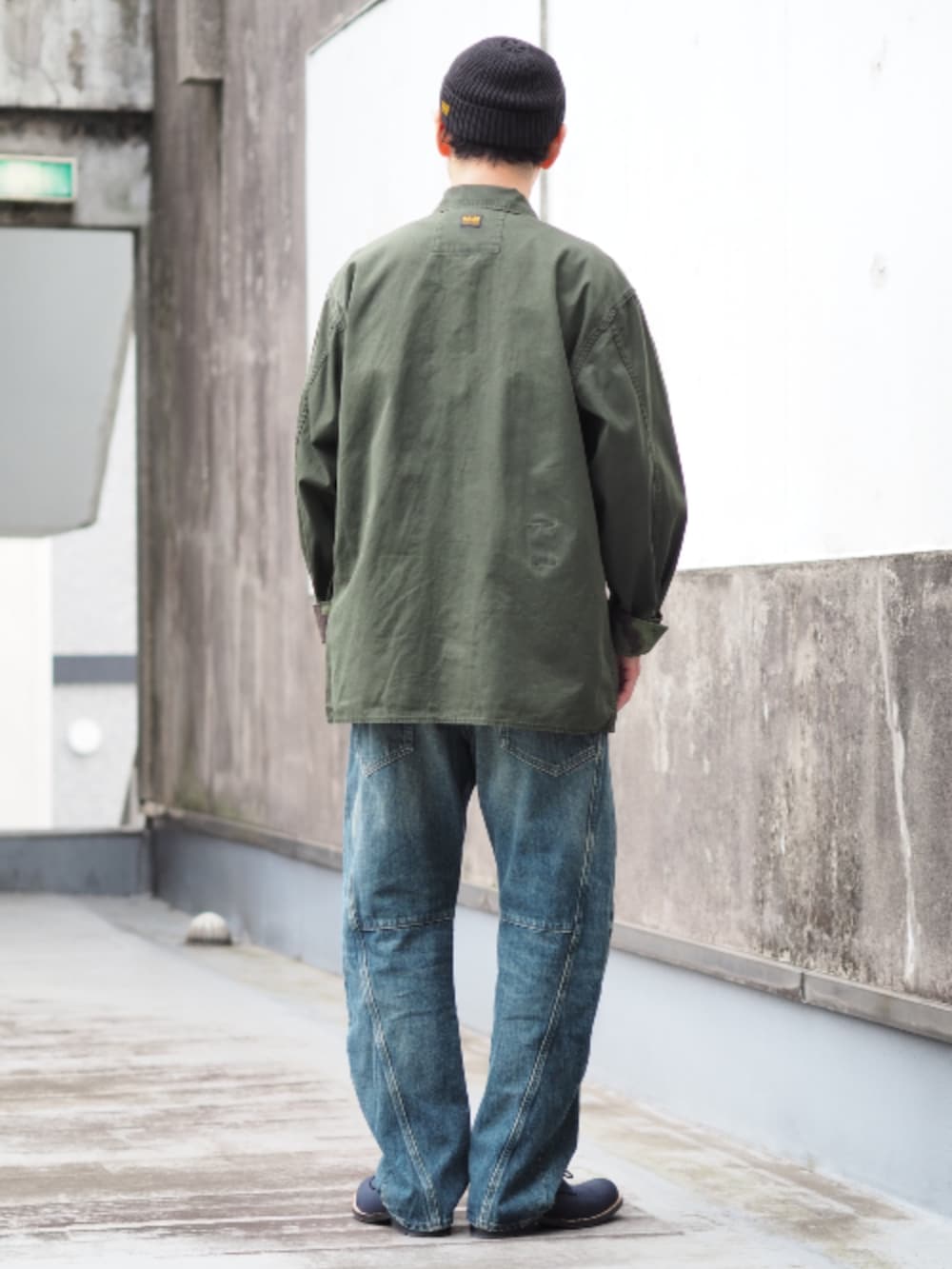 グリーン系のミリタリージャケット、ブルー系のデニムパンツを着用したメンズの春コーディネートの2枚目の写真