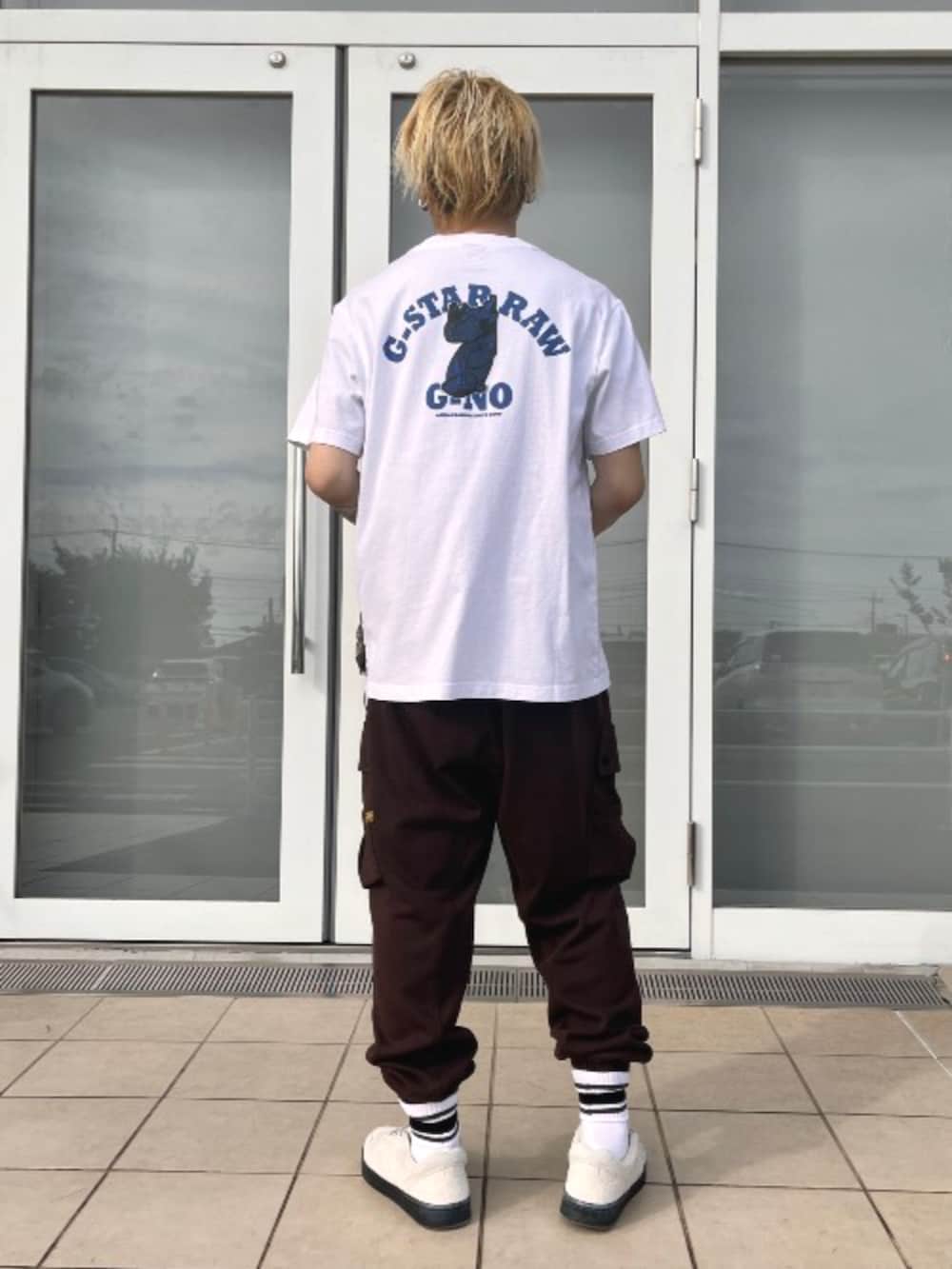 ホワイト系のTシャツ/カットソー、ベージュ系のナイロンジャケット、ブラウン系のスウェットパンツを着用したメンズの夏コーディネートの2枚目の写真