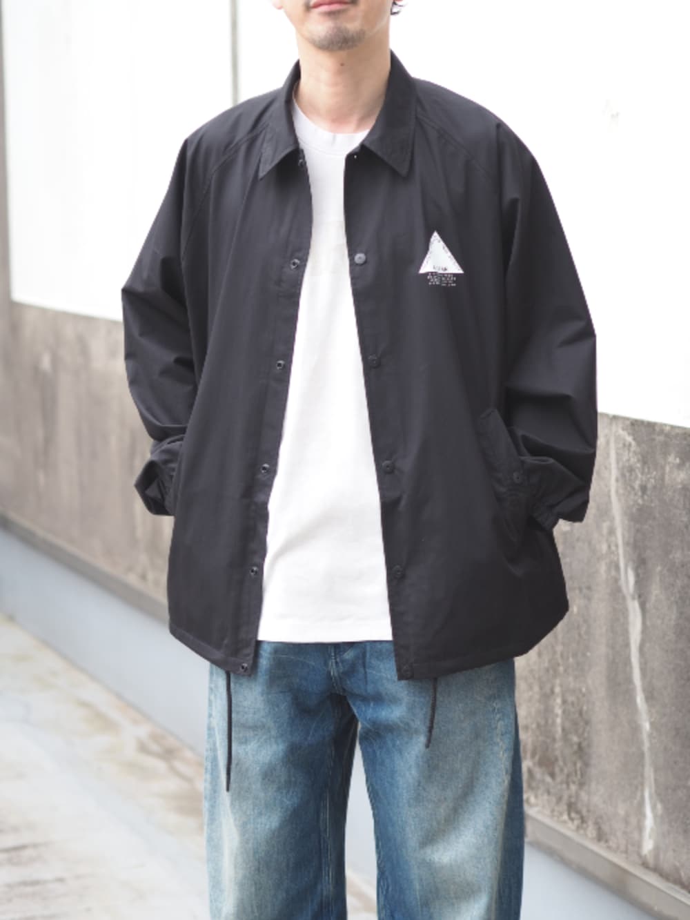 ブラック系のナイロンジャケット、ブルー系のデニムパンツ、ホワイト系のTシャツ/カットソーを着用したメンズの春コーディネートの3枚目の写真