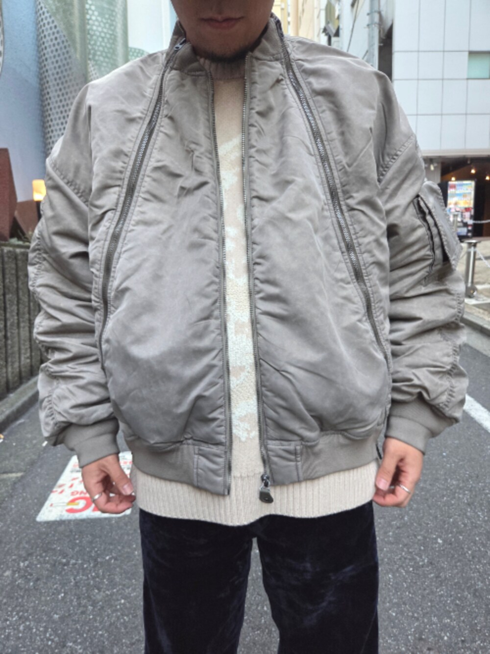 ベージュ系のMA-1、ベージュ系のニット/セーター、ブルー系のデニムパンツを着用したメンズの秋コーディネートの2枚目の写真