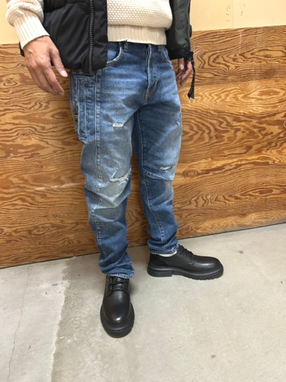 ブラック系のドレスシューズ、ブルー系のダウンベスト、ベージュ系のニット/セーターを着用したメンズの秋コーディネートの3枚目の写真